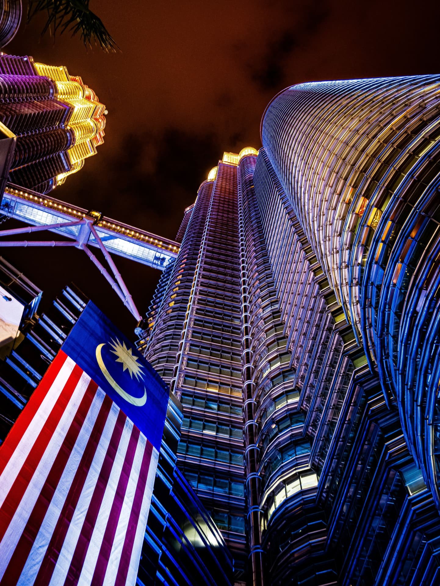 Kuala Lumpur skyline at night with the Malaysian flag and Petronas Towers
